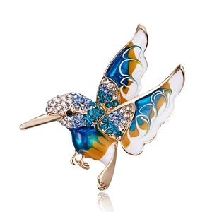 Macro detail of hummingbird brooch with blue enamel wings and sparkling rhinestones