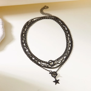 Close-up of black layered metal chain necklace with OT buckle and star pendant detail