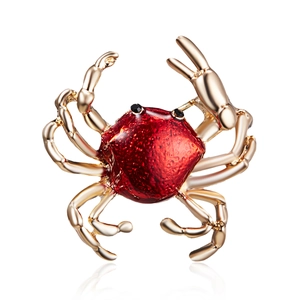 Detailed view of a golden crab brooch featuring red enamel shell and black bead eyes