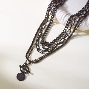 Detail of black multi-layer chain necklace featuring a vintage toggle clasp and round pendant