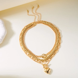 Detail of layered gold-tone necklace featuring heart pendant and toggle clasp closure