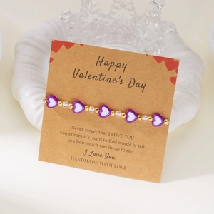 Dettaglio del bracciale con cuori viola e biglietto regalo festivo per San Valentino