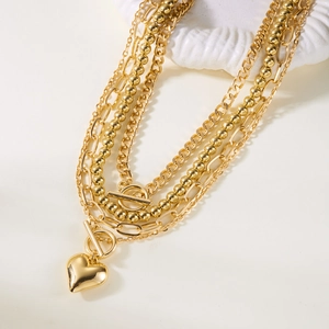 Detail of gold multi-layer necklace set with heart pendant and stylish toggle clasp