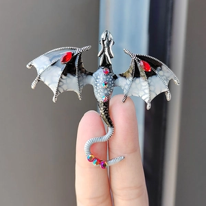 Detailed view of silver dragon brooch with black enamel, red rhinestones and crystals
