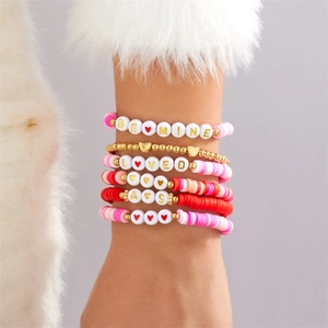 Nahaufnahme von mehrlagigen Perlenarmbändern mit Herzanhängern und Schriftzug