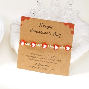 Dettaglio del bracciale con perline a cuore su carta kraft per regalo di San Valentino