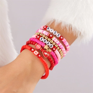 Nahaufnahme von rosa Herzanhängern und bunten Perlenarmbändern an einem Handgelenk