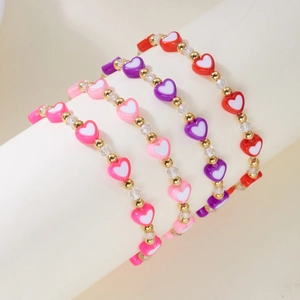 Set di quattro braccialetti con perline a cuore colorate e accenti dorati su supporto