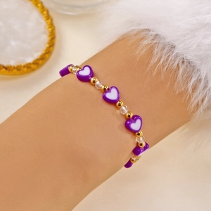 Grazioso bracciale con perline a cuore viola, accenti dorati e cristalli sul polso