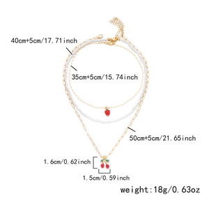Details einer dreilagigen Goldkette mit roten Kirschen, Erdbeeren und weißen Perlen
