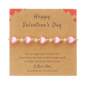 Bracciale con perle a cuore rosa e bianche su carta regalo di San Valentino con oro