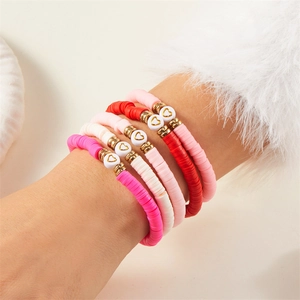 Nahaufnahme gestapelter rosa Herz-Tonperlen-Armbänder im modischen Boho-Look getragen