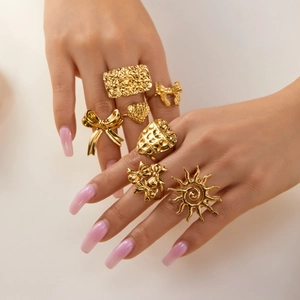 Close-up of golden stainless steel rings with heart, sun and butterfly motifs on fingers