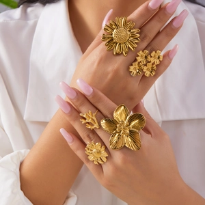 Close-up of a model wearing five gold floral rings with sunflower and coral designs