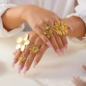 Detailed view of five gold-toned rings featuring sunflower, plum blossom, and coral designs