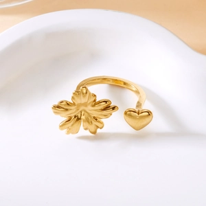 Close-up of golden adjustable ring with petal and heart charms on a ceramic plate