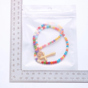 Detail view of colorful natural stone beaded necklace with gold cross pendant next to ruler