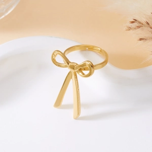 Macro detail of adjustable golden bow ring featuring a matte finish and elegant curved lines