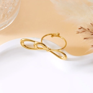 Detailed view of an adjustable golden bow ring on an elegant ceramic display tray