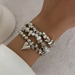 Dettaglio di braccialetti multistrato in argento con pendente a cuore e perle