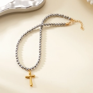 Detail of silver beaded chain with gold cross pendant and lobster clasp adjustment
