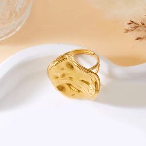 Detailed macro view of the gold irregular hammered molten textured ring on a ceramic tray