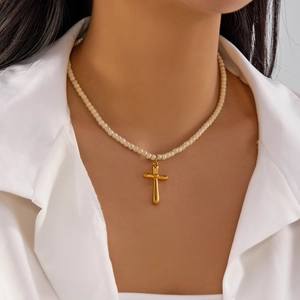 Close-up of golden cross pendant on natural stone beaded necklace worn on neck