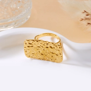 Detail of golden rectangular ring featuring a unique hammered texture finish on a stand