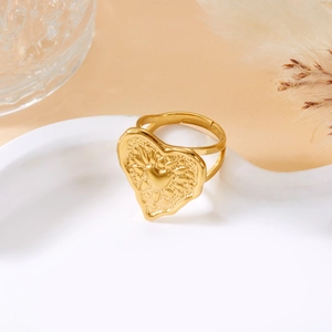 Macro view of a gold heart ring with sunburst texture and split band on white tray