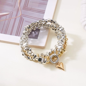 Detailaufnahme eines dreilagigen Perlenarmbands mit goldenem Herzanhänger und Metallperlen
