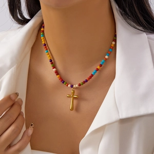 Detail of colorful stone beaded necklace with a golden cross pendant on a model