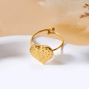 Macro shot of gold heart ring with pebble texture and adjustable band on white tray
