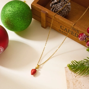 Détail du collier doré avec pendentif fraise émaillé rouge et décorations de fête