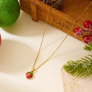 Détail d'un collier pendentif fraise rouge avec chaîne dorée dans un décor de Noël festif