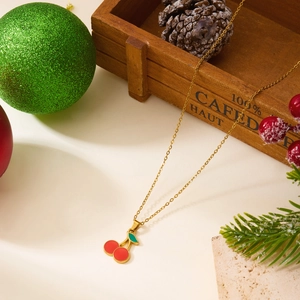 Détail d'un collier pendentif cerise en émail rouge avec des décorations de Noël festives
