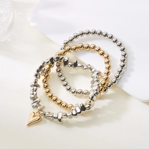 Detail von mehrlagigen Perlenarmbändern mit silbernen Würfeln und goldenem Herzanhänger