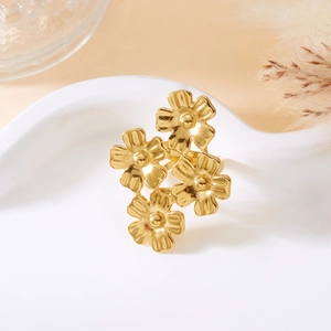 Detailed view of an adjustable golden four-flower ring placed on a white heart ceramic tray