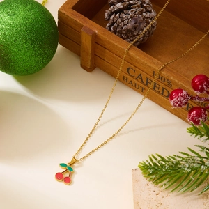 Détail du collier cerise avec émail rouge et vert sur une chaîne dorée fine