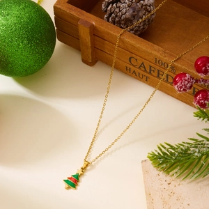 Détail d'un collier doré avec un pendentif sapin de Noël festif en émail rouge et vert