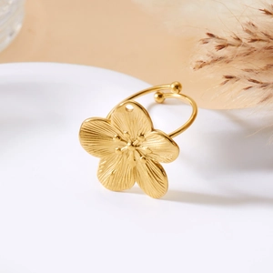 Detailed close-up of golden flower ring with textured petals on a ceramic tray