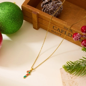 Détail du collier canne à sucre de Noël doré avec émail rouge et vert sur fond festif