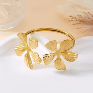 Makro-Detail des goldenen Blumenarmreifs mit gebürsteter Textur und Blütenblatt-Gravur
