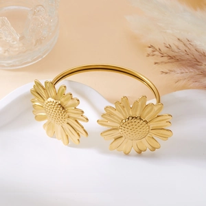 Makro-Detail des goldenen Sonnenblumen-Armreifs auf elegantem strukturiertem Hintergrund