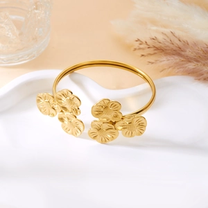 Detail eines goldenen Edelstahl-Armreifs mit filigranen, hohlen Blumen-Verzierungen