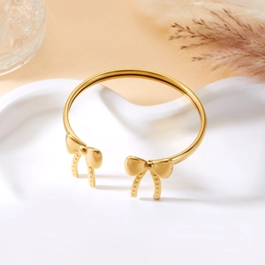 Detail eines goldenen Armreifs mit Schleifenknoten auf weißem Keramiktablett
