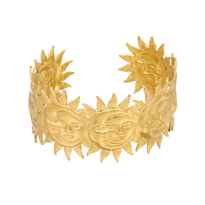 Macro view of gold sun face relief on wide cuff bracelet with a brushed metal texture