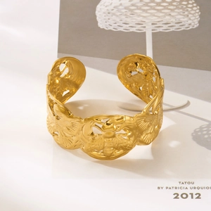 Macro shot of gold cuff bracelet featuring intricate bee and floral relief carvings