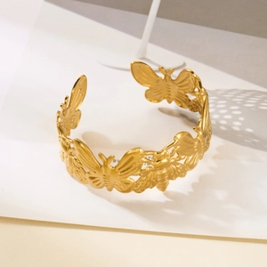 Macro detail of golden butterfly relief cuff bracelet with matte stainless steel finish