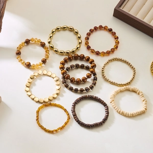 Detail of bohemian stretch bead bracelets featuring natural wood and golden metal charms