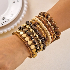 Detail of bohemian stackable beaded bracelets featuring gold metal and wooden beads